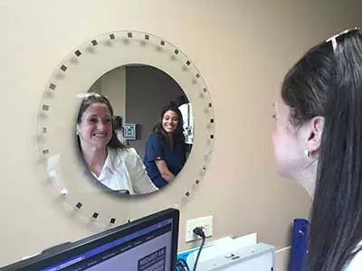 patient checking out her teeth in the mirror at Center for Cosmetic Dentistry