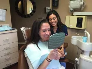 patient checking out her teeth after getting them cleaned at Center for Cosmetic Dentistry